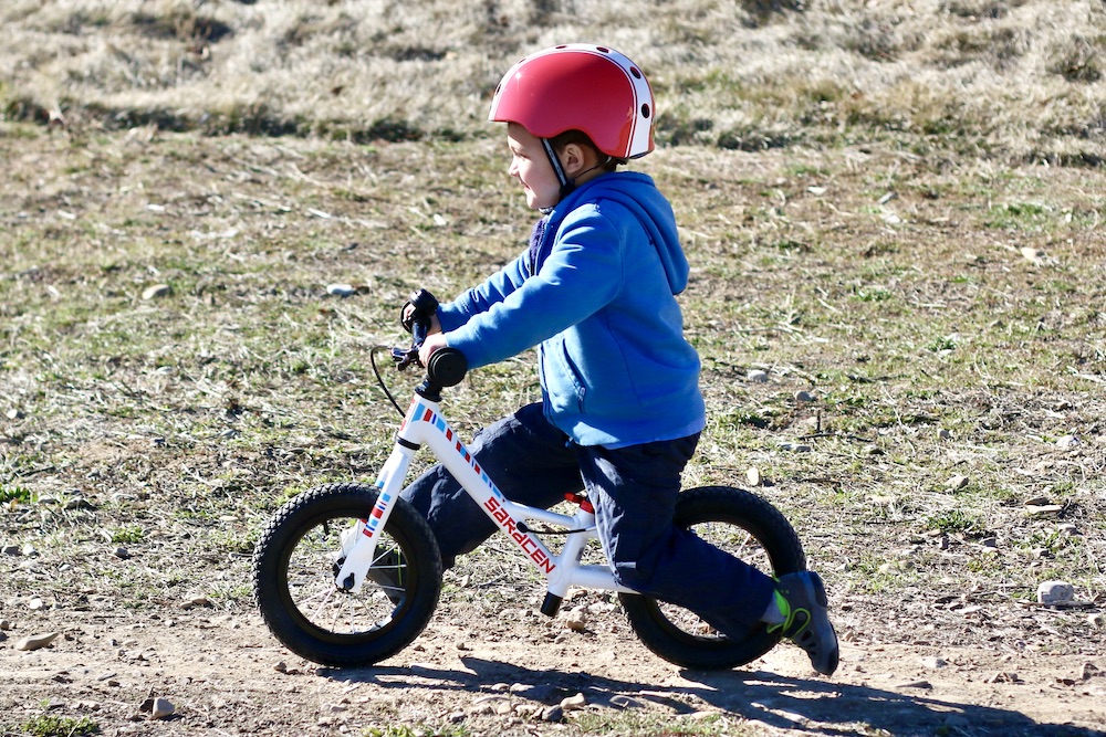 preschooler riding the saracen freewheel balance bike on a dirt track
