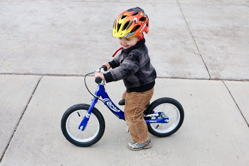 child riding a blue kinderbike balance bike