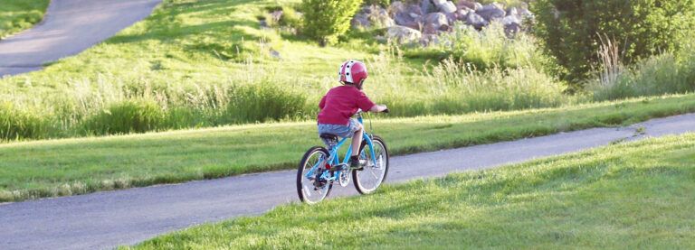 young boy riding a blue Priority Start 20 inch bike