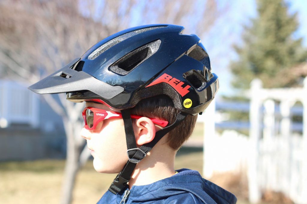 a side profile image of a boy wearing a black bell nomad jr bike helmet