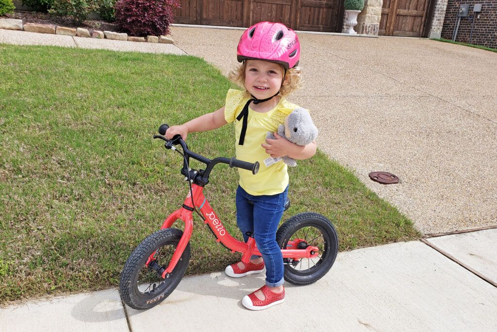 young toddler riding a pink pello ripple balance bike