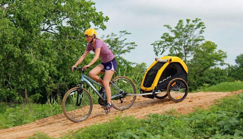 woman riding a bike with a burley bee bike trailer