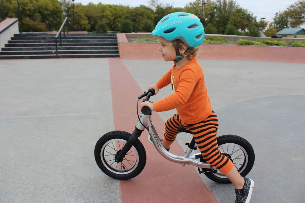 young girl riding a silver balance bike