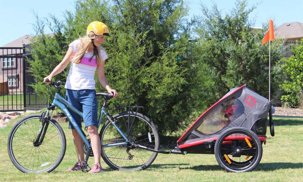 mom pulling their daughter behind her bike in a hamax outback bike trailer