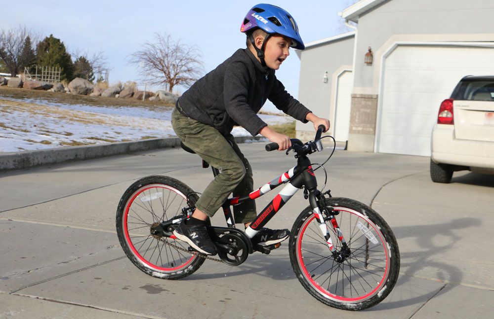 young boy riding a guardian bike while wearing the lazer gekko helmet