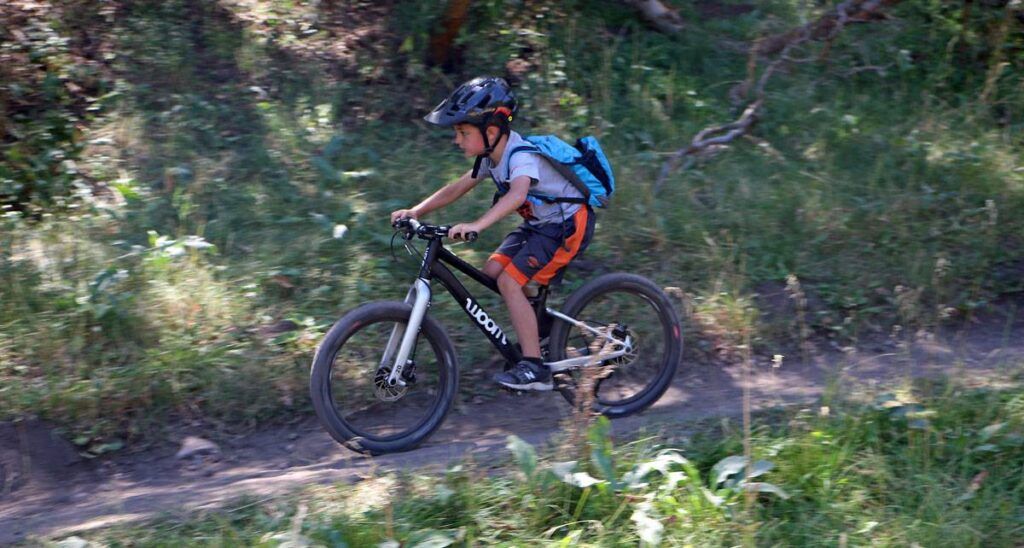 young child riding a 20 inch mountain bike down a single track trail
