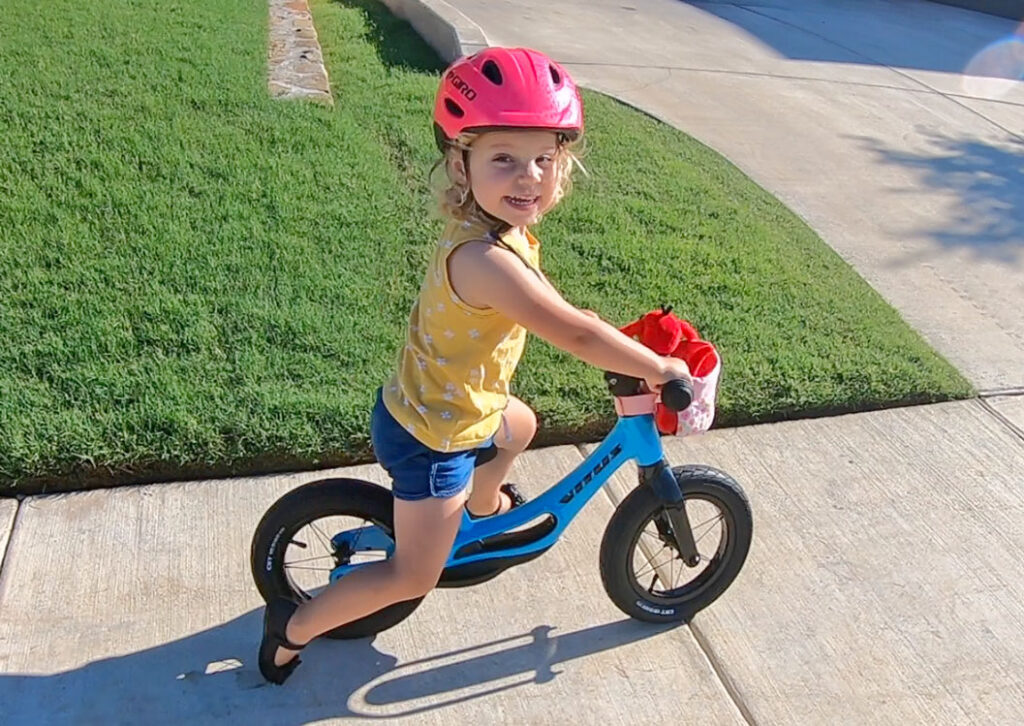Toddler riding Vitus Smoothy balance bike down the sidewalk