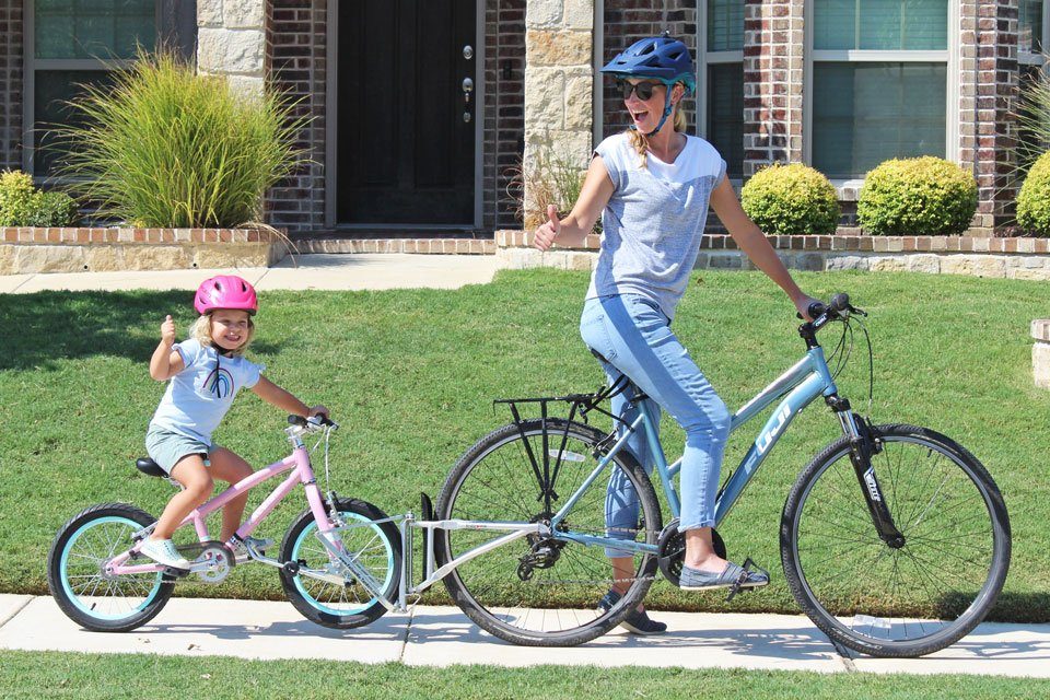 Mom and daughter on bikes, connected by the FollowMe Tandem bike coupling device