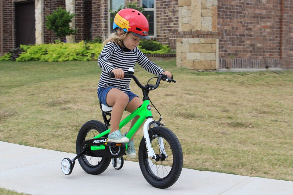 Young girl riding 14 inch Royal Baby bike with training wheels