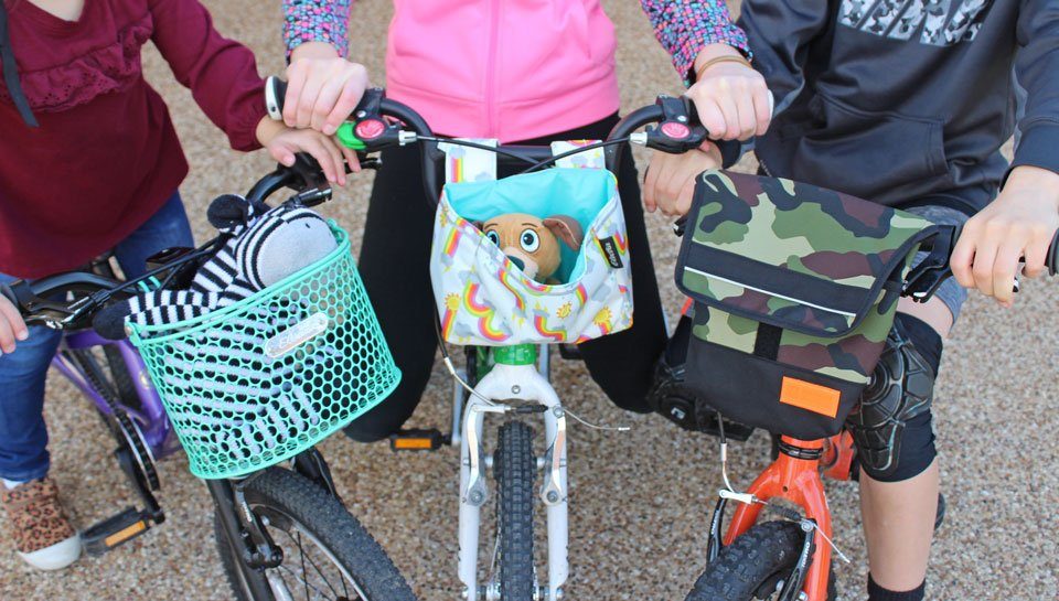 Three kids bike baskets lined up and attached onto kids bikes.