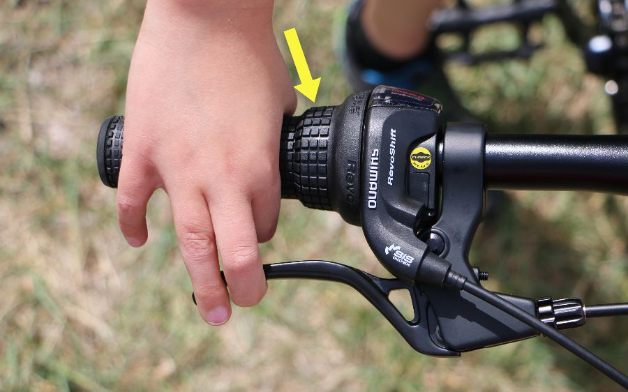 boys hand trying to reach the brake levers while using the Shimano Tourney Revoshift grip shifters.  His fingers have to angle across the grip in order to reach the brake lever.