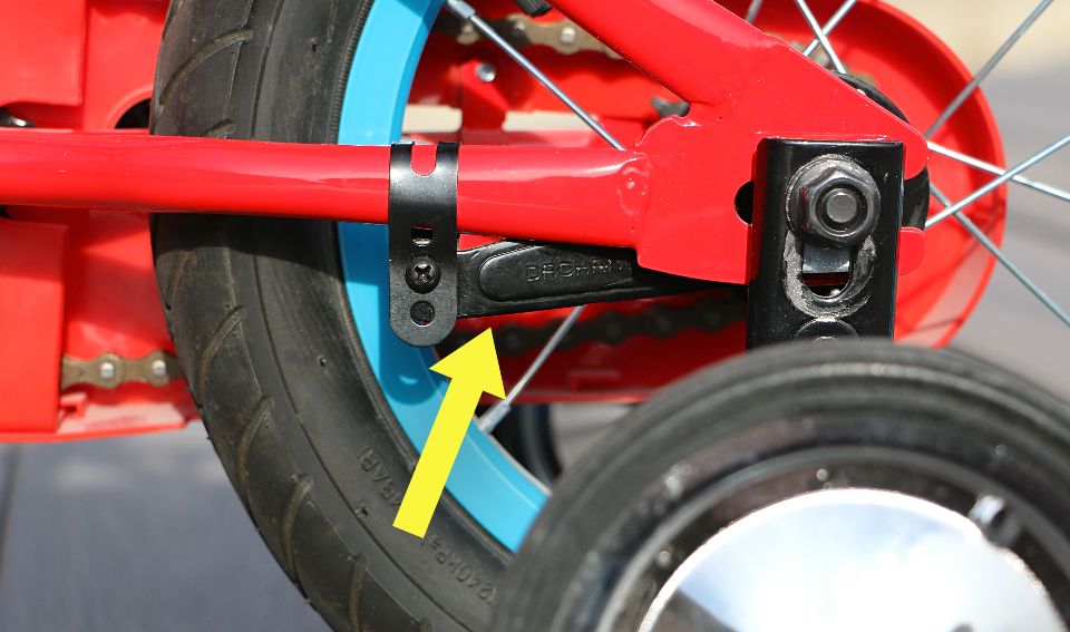 arrow pointing to a black coaster brake arm on a kids bike