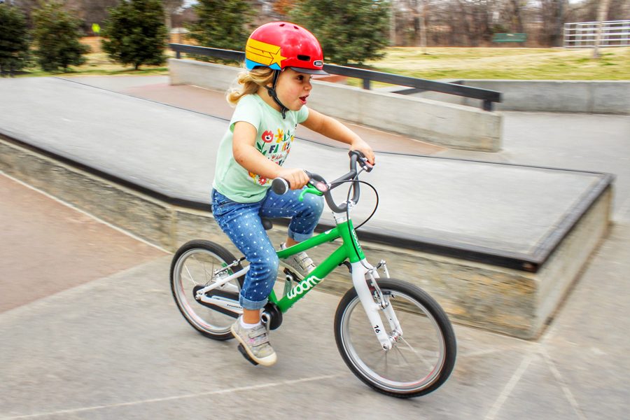 child riding woom 3 16 inch green bike down a ramp 