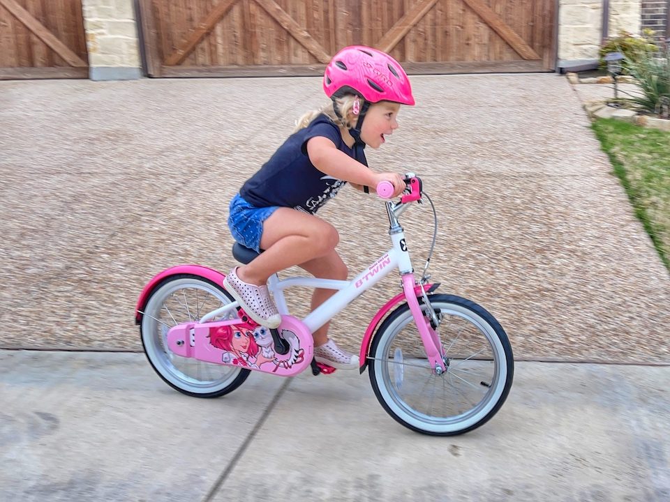 Young girl riding Btwin HYC 500 16 inch kids bike in pink