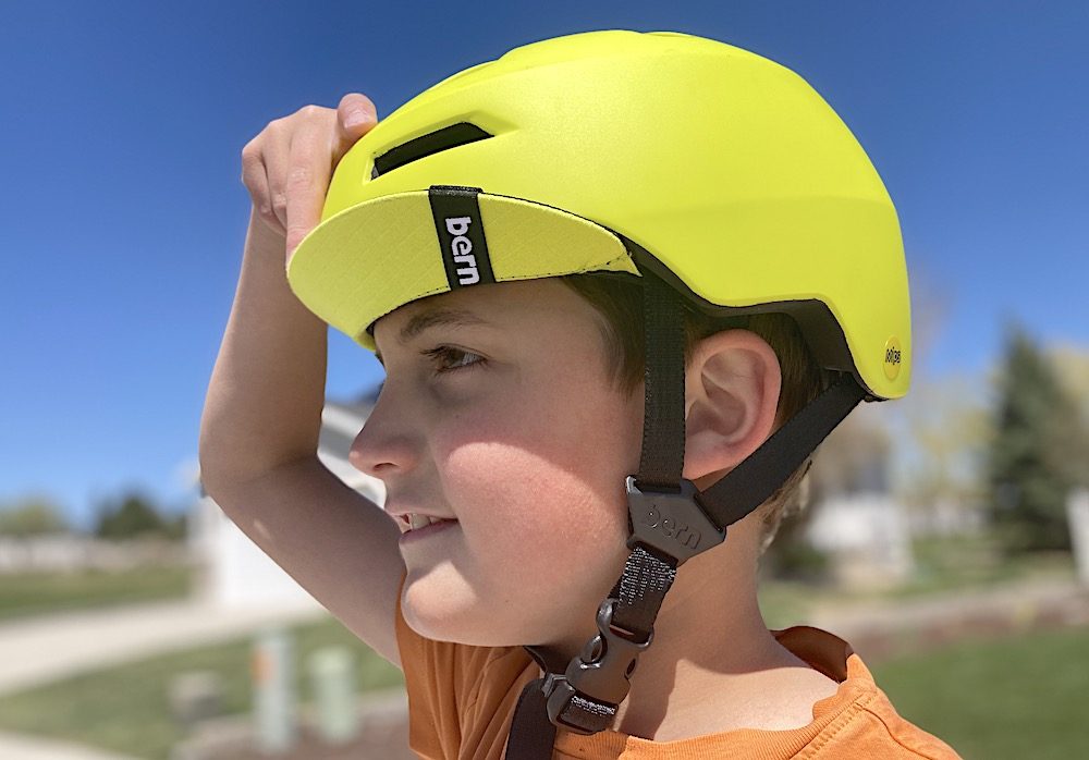young boy wearing a yellow bern kids bike helmet with the visor flipped up