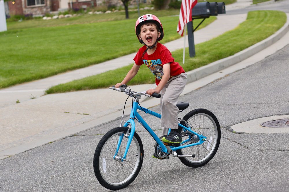 Young boy happily riding the Priority Start 20 inch bike