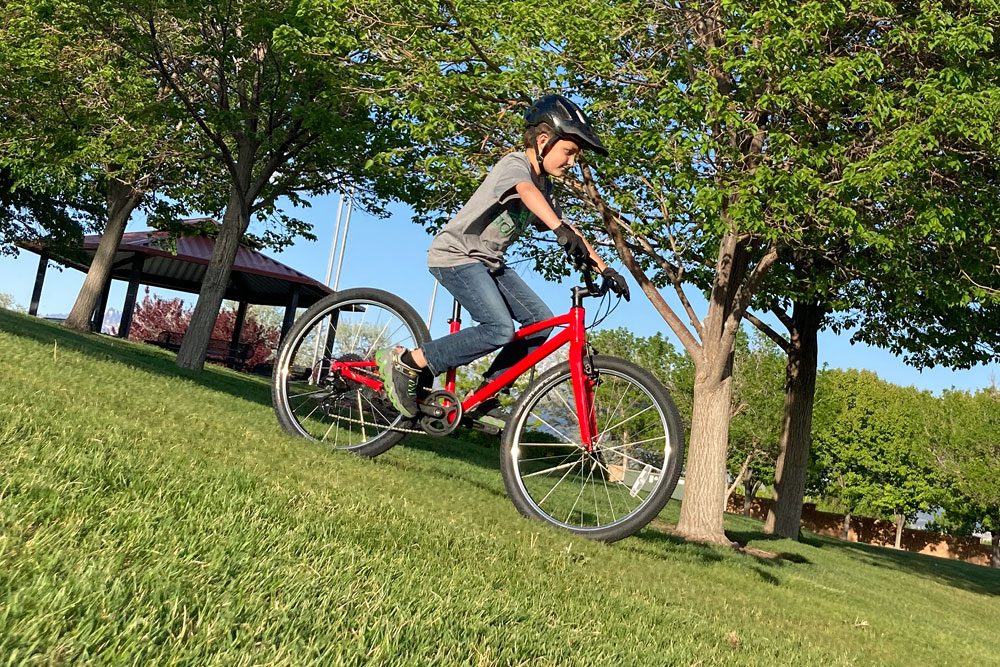 boy riding down a grassy hill on the Specialized Jett kids bike