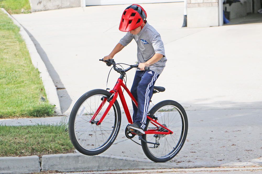 young boy jumping the Specialized Jett off a curb