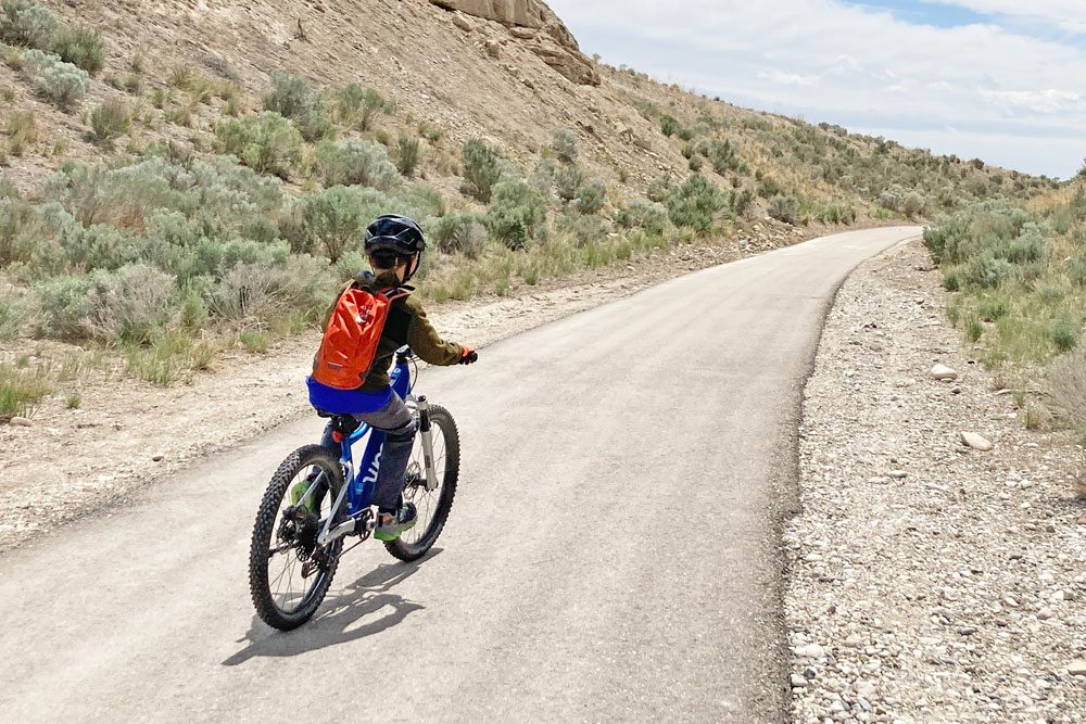 child riding a kids ebike on a paved bike trail