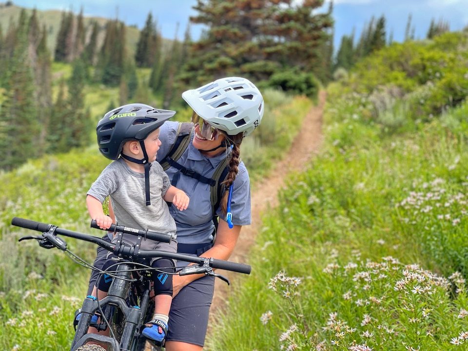 Mom and son smiling each other while mountain biking with Shotgun Pro seat