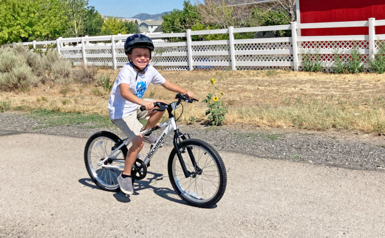 Child smiling while riding down road on Btwin Rockrider 20 inch bike