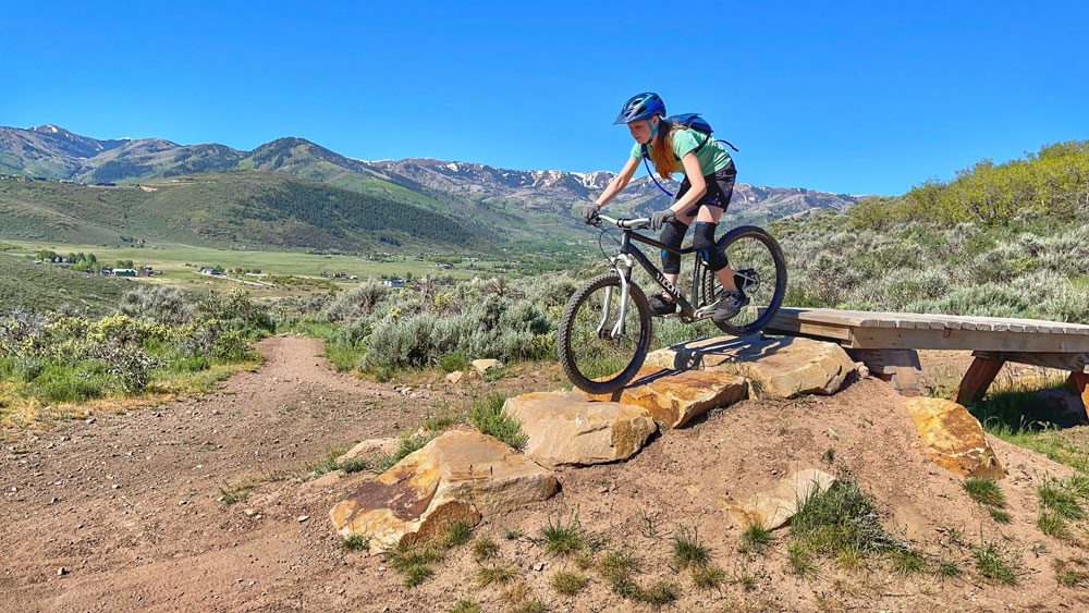 girl riding down a rock garden in the mountains on the woom OFF AIR 6