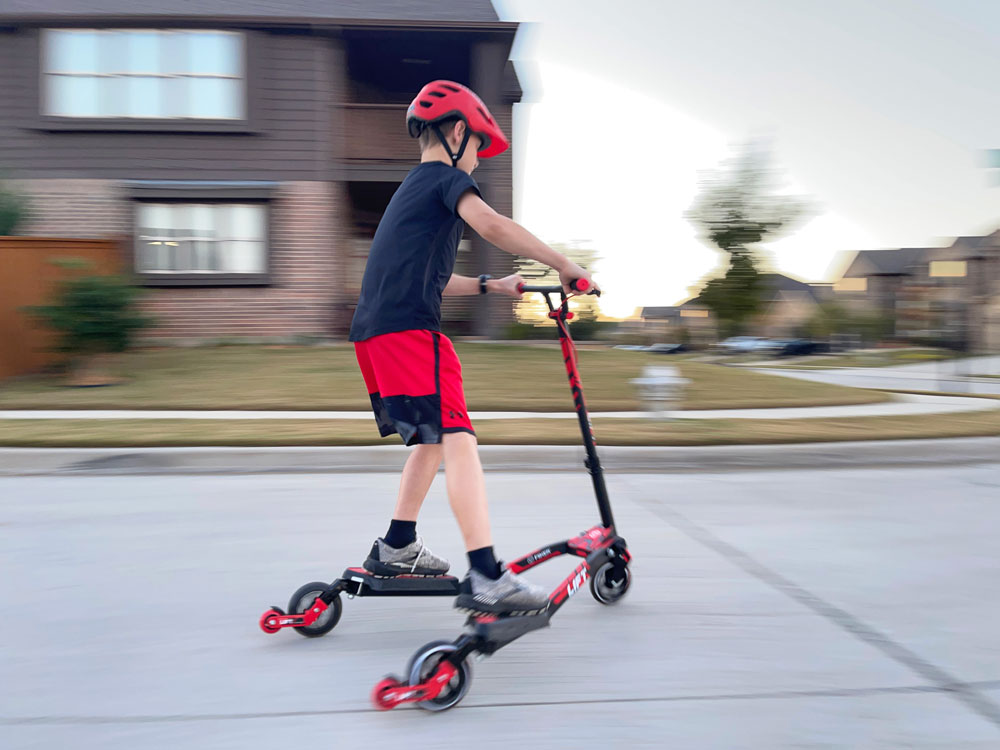 Boy speeding down hill on Y fliker scooter