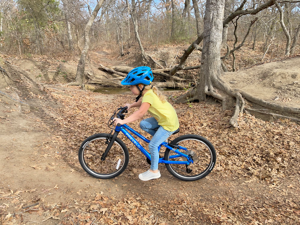 Child riding Prevelo Alpha Three 20 inch bike on a dirt trail