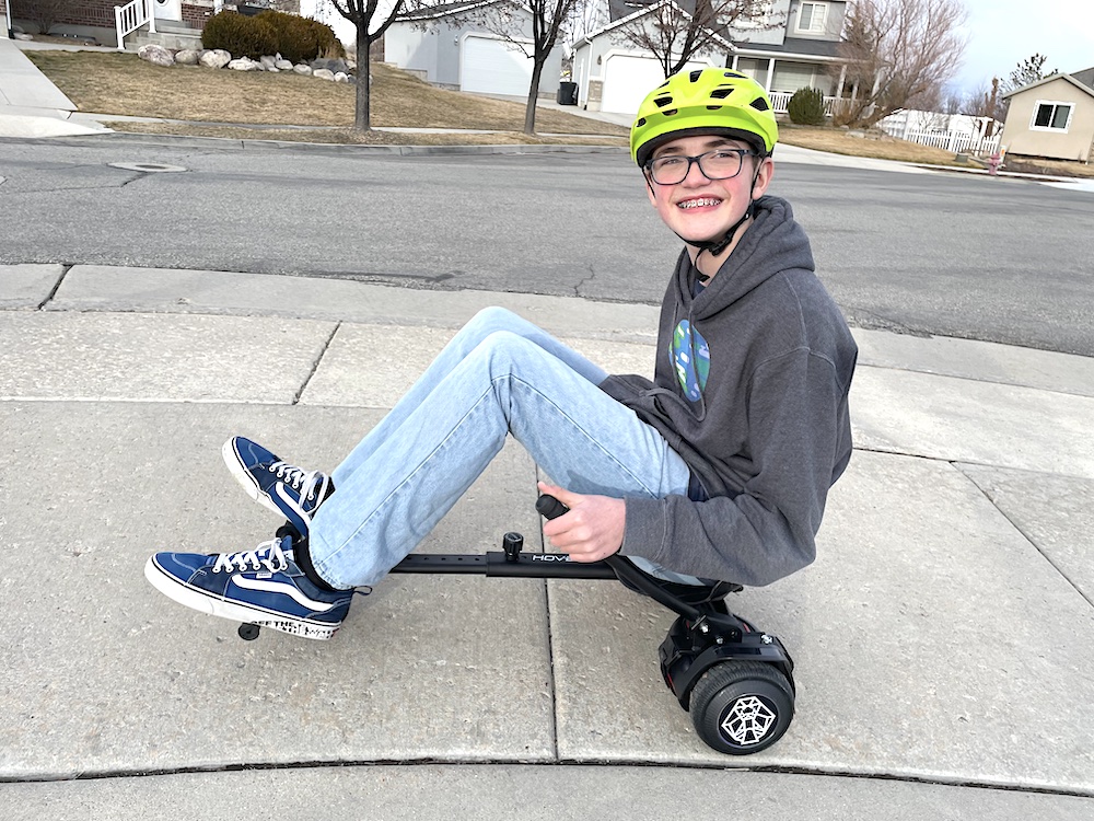 年轻男孩在自家门前骑着 Hover-1 猎鹰悬浮滑板推车
