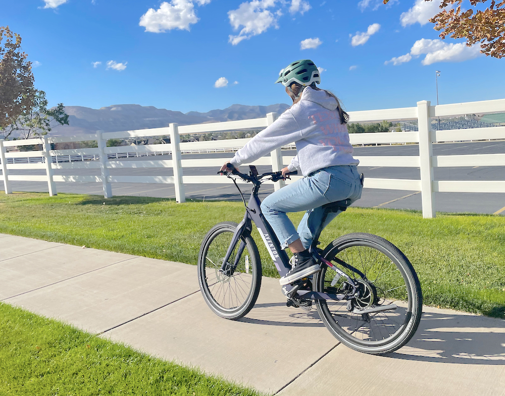 Woman riding Aventon Pace 350 electric bike down the sidewalk