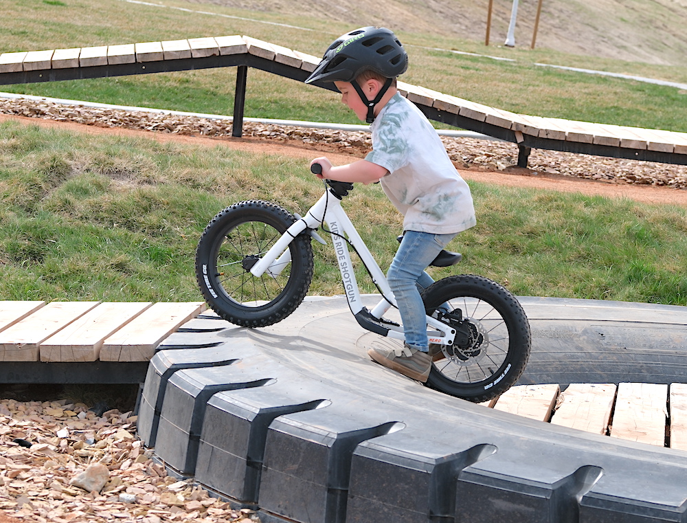 toddler lifting DIrt Hero off-road balance bike up over an obstacle