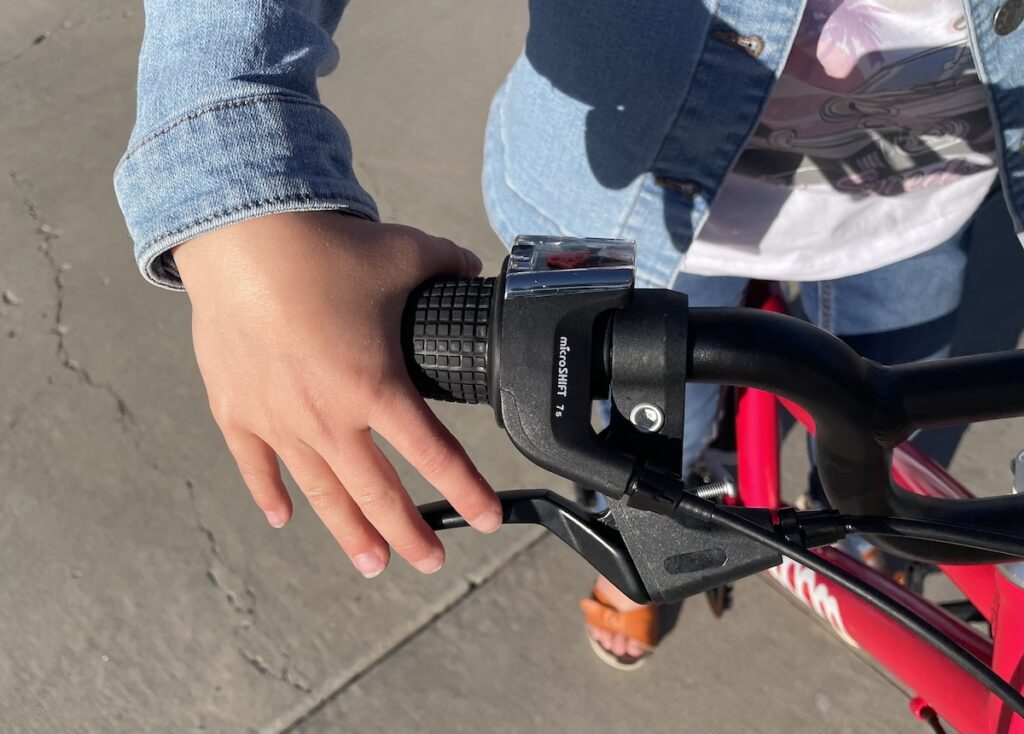 a child’s hand pulling the brake lever on a woom GO 4