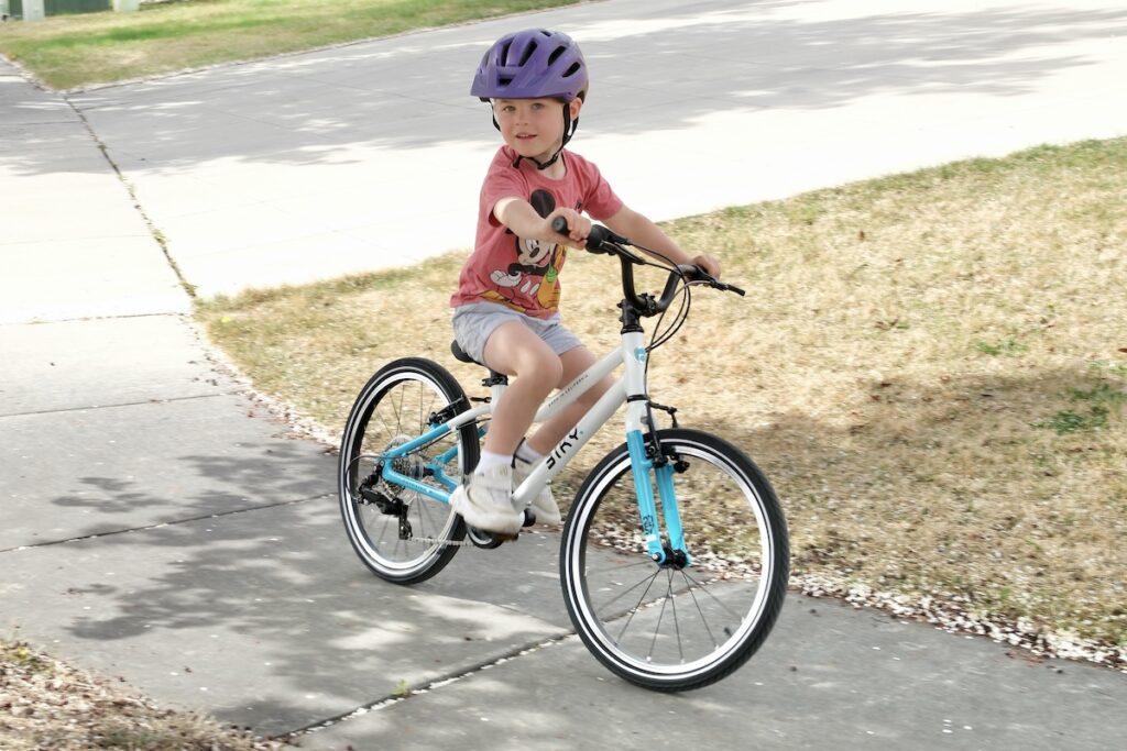 young boy riding the biky air 20 on the sidewalk
